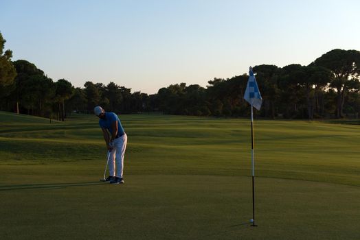 golf player hitting ball  with driver on course at beautiful sunset