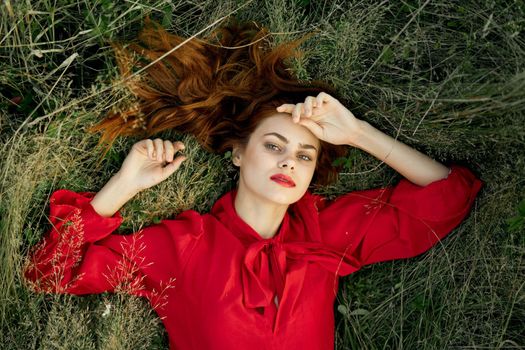 woman in red dress lies on the grass nature freedom summer. High quality photo