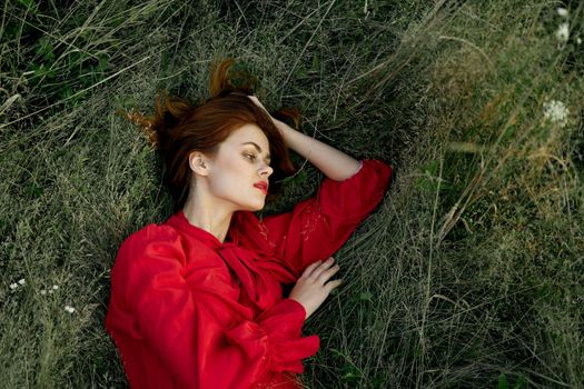 woman in red dress lies on the grass nature freedom summer. High quality photo