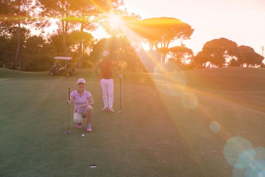 portrait of happy young  couple on golf course with beautiful sunset in background