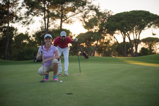 portrait of happy young  couple on golf course with beautiful sunset in background