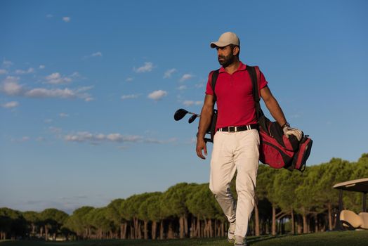 handsome middle eastern golfer  carrying  golf bag  and walking at course to next hole