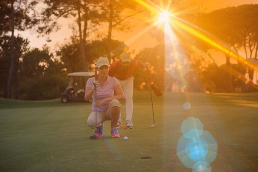 portrait of happy young  couple on golf course with beautiful sunset in background