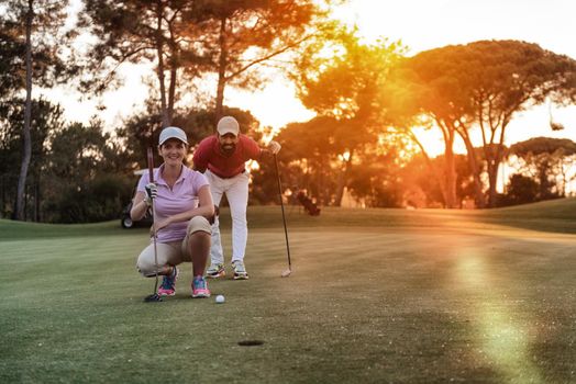 portrait of happy young  couple on golf course with beautiful sunset in background