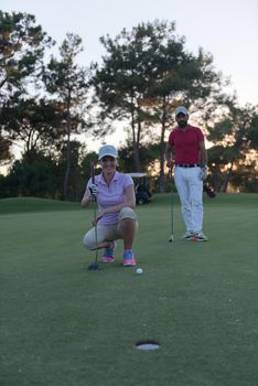 portrait of happy young  couple on golf course with beautiful sunset in background