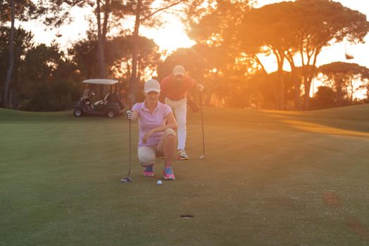 portrait of happy young  couple on golf course with beautiful sunset in background