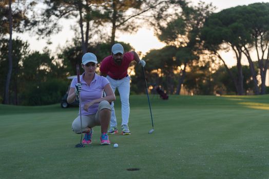 portrait of happy young  couple on golf course with beautiful sunset in background