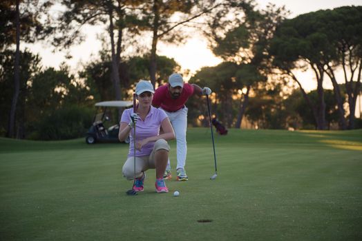 portrait of happy young  couple on golf course with beautiful sunset in background