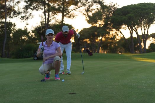 portrait of happy young  couple on golf course with beautiful sunset in background