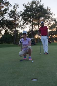 portrait of happy young  couple on golf course with beautiful sunset in background