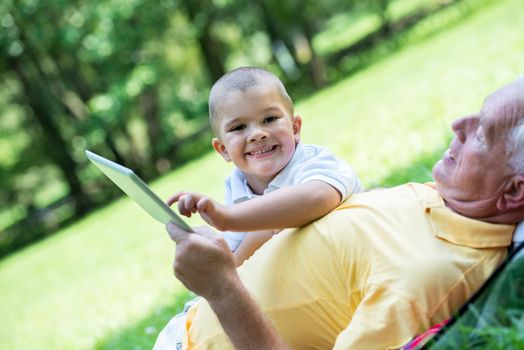 grandfather and child using tablet computer in park