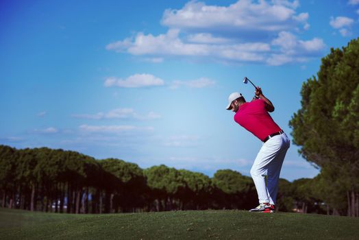 golf player hitting shot with driver on course at beautiful sunny day