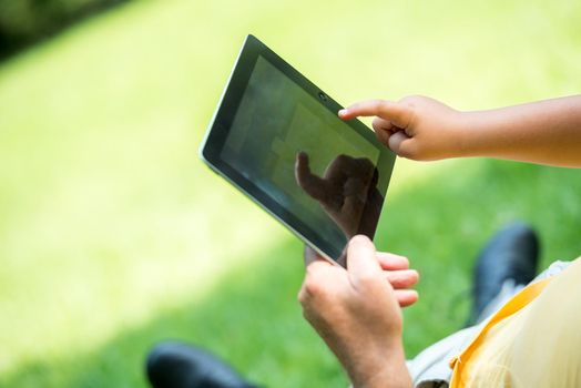 grandfather and child using tablet computer in park