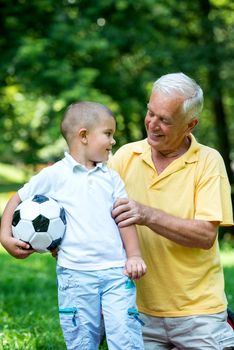 happy elderly senior grandfather and child in park using laptop computer