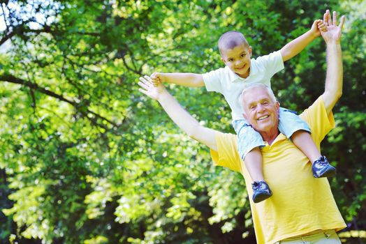 happy grandfather and child have fun and play in park