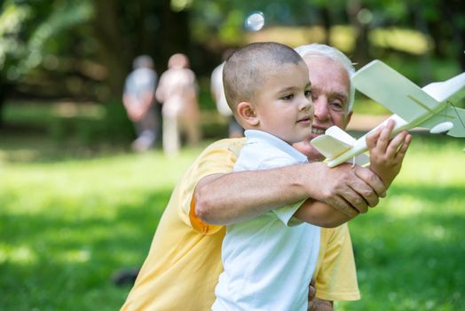 happy grandfather and child have fun and play in park on beautiful  sunny day