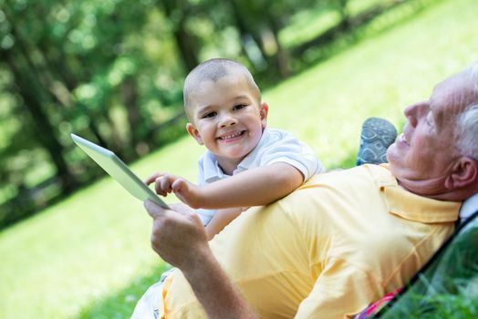 grandfather and child using tablet computer in park