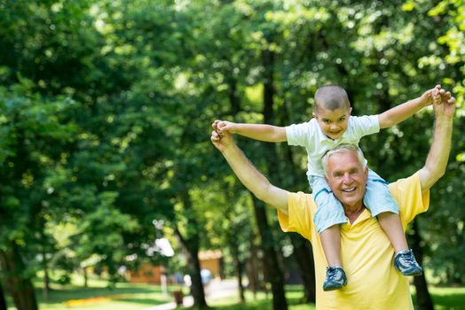 happy grandfather and child have fun and play in park on beautiful  sunny day