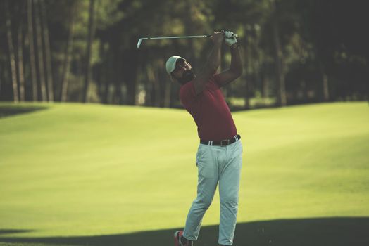 golf player hitting shot with driver on course at beautiful sunny day