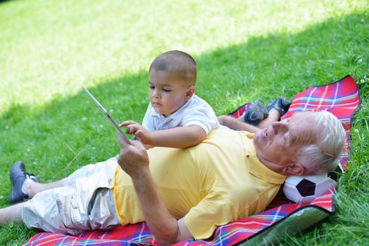 grandfather and child in park using tablet computer