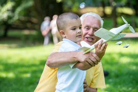 happy grandfather and child have fun and play in park on beautiful  sunny day