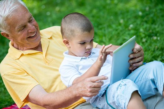 grandfather and child using tablet computer in park