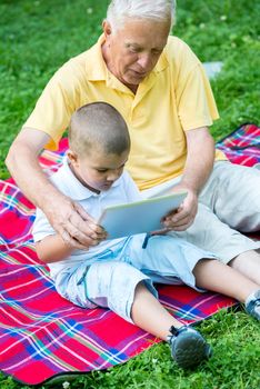 grandfather and child using tablet computer in park