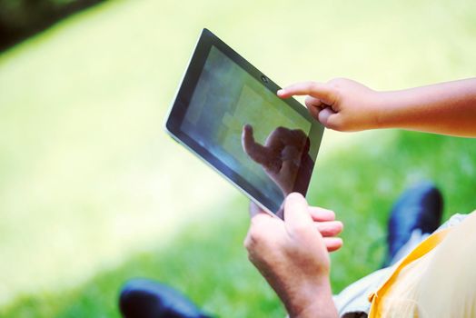 grandfather and child using tablet computer in park