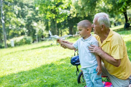 happy grandfather and child have fun and play in park on beautiful  sunny day