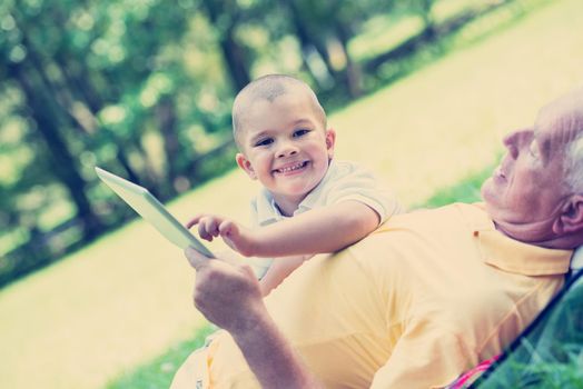 grandfather and child using tablet computer in park