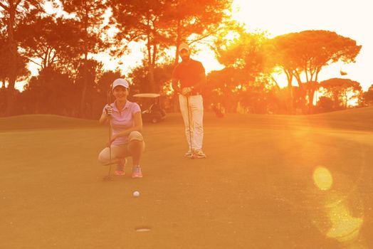 portrait of happy young  couple on golf course with beautiful sunset in background