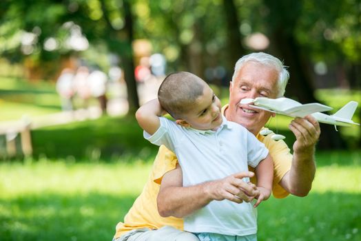 happy grandfather and child have fun and play in park on beautiful  sunny day