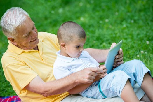 grandfather and child using tablet computer in park