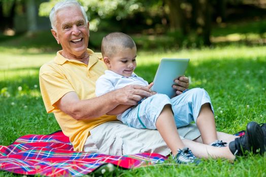 grandfather and child using tablet computer in park