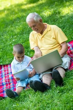 grandfather and child using tablet computer in park