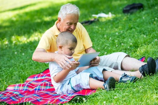 grandfather and child using tablet computer in park