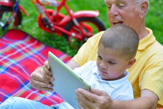 grandfather and child in park using tablet computer