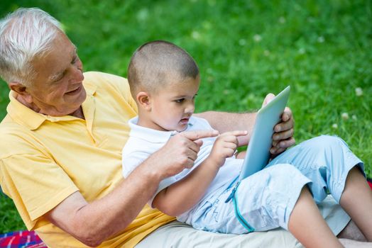 grandfather and child using tablet computer in park