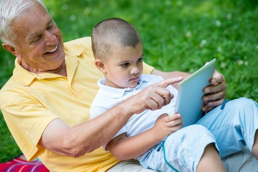 grandfather and child using tablet computer in park