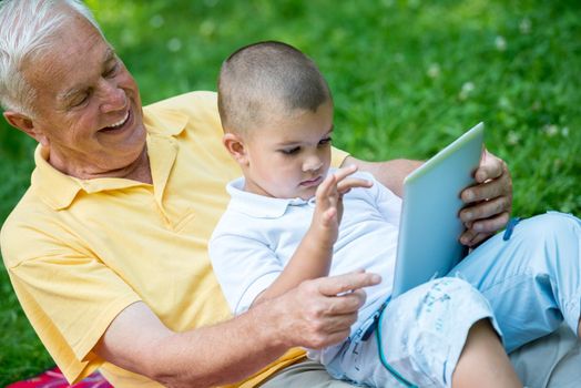 grandfather and child using tablet computer in park