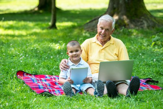 grandfather and child using tablet computer in park