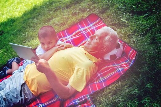 grandfather and child using tablet computer in park