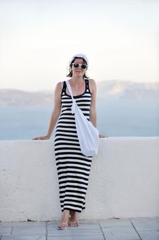 Beautiful young Greek woman in fashion clothes have fun at n the streets of Oia, Santorini, Greece