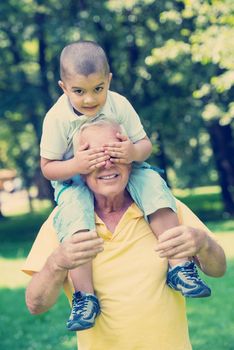 happy grandfather and child have fun and play in park on beautiful  sunny day