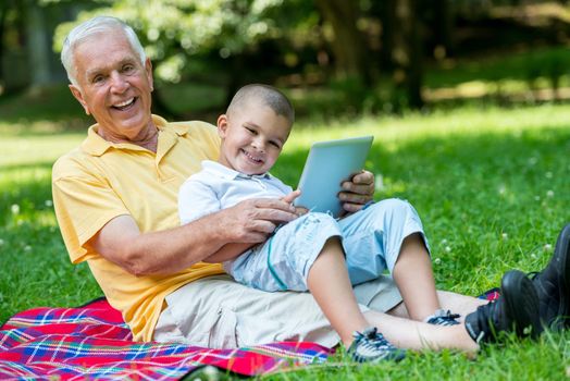 grandfather and child using tablet computer in park