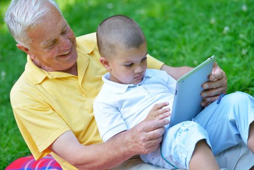 grandfather and child in park using tablet computer