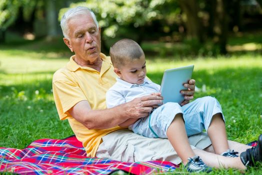 grandfather and child using tablet computer in park