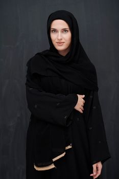 Modern young muslim woman in black abaya. Arab girl wearing traditional clothes and posing in front of black chalkboard. Representing modern and rich arabic lifestyle