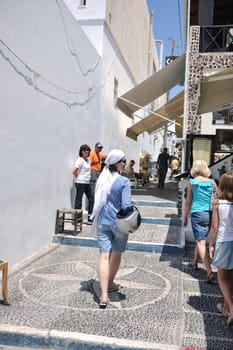 Beautiful young Greek woman in fashion clothes have fun at n the streets of Oia, Santorini, Greece