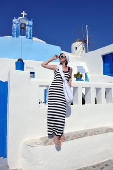 Beautiful young Greek woman in fashion clothes have fun at n the streets of Oia, Santorini, Greece
